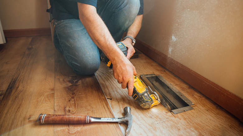 A person using an oscillating tool to cut wood flooring