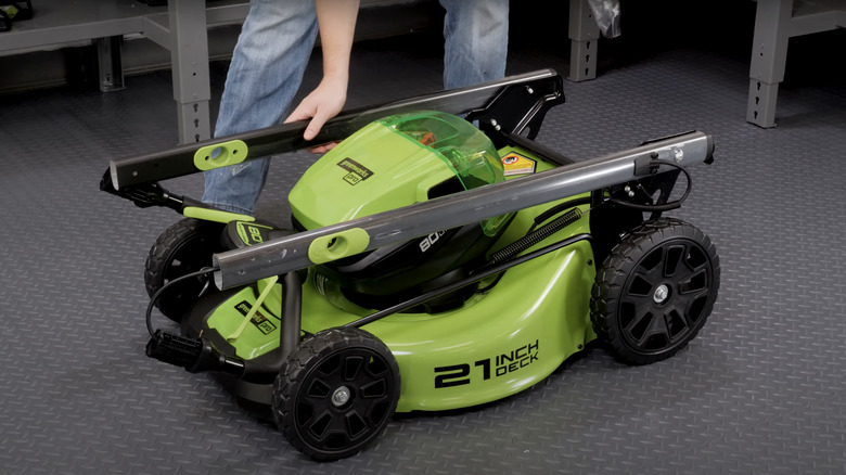 man assembling small lawn mower indoors