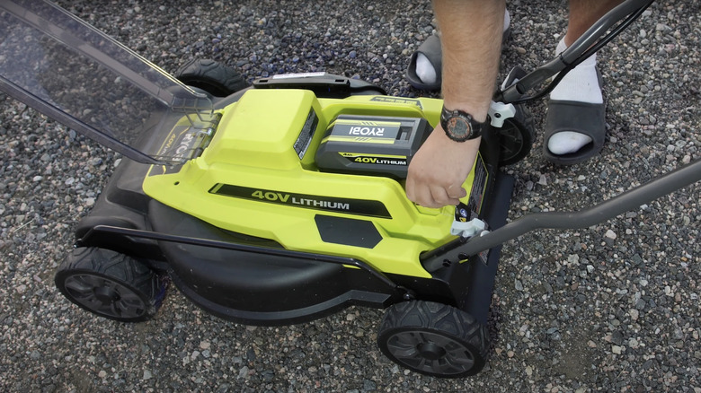 man removing green lawn mower battery