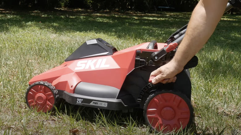 man adjusting small red mower