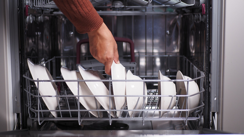 Hand taking out dishes from dishwasher