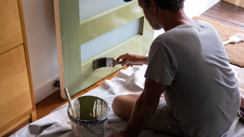 man paints door