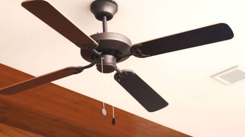 Brown pull chain ceiling fan against white ceiling