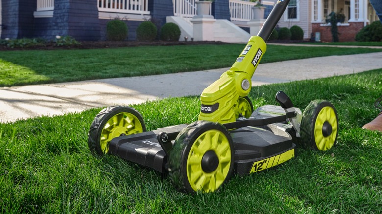 A person pushing a Ryobi mower, trimmer, and edger