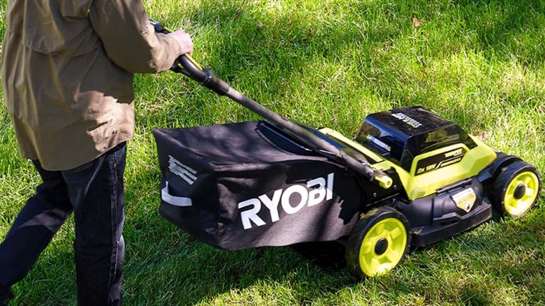 A man pushing an 18V Ryobi lawn mower