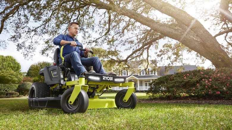 A man riding a zero-turn Ryobi lawn mower