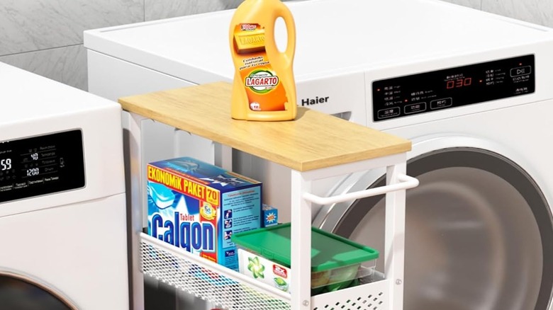 A rolling cart with cleaning supplies between a washer and dryer