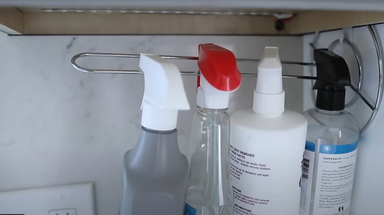 A paper towel holder serving as a hanging rod for cleaning supplies