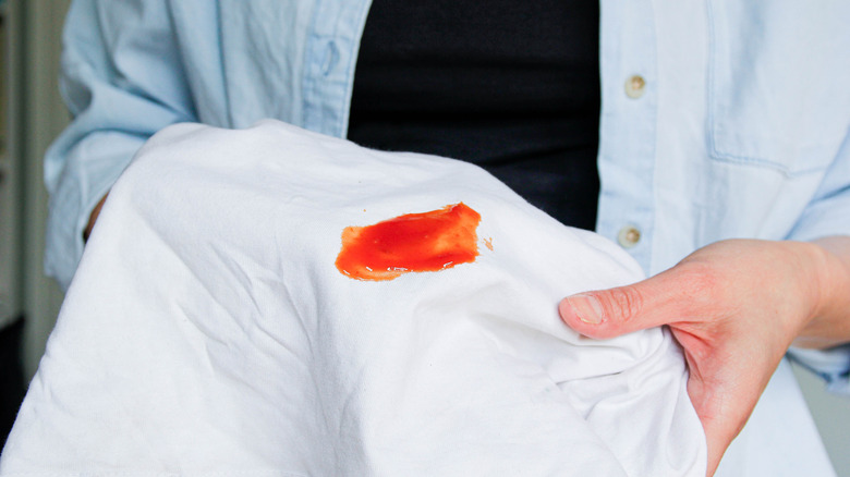 Person holding white sheet with red stain