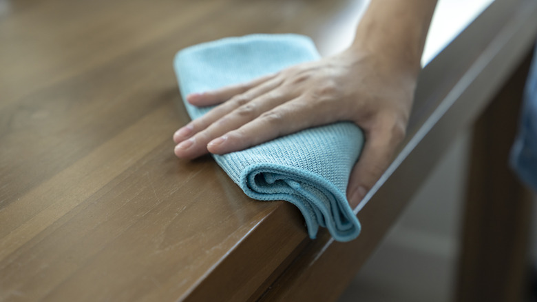 Person polishing wood furniture with a cloth