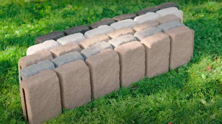 Faux driveway edging stones in different colors next to each other in the grass