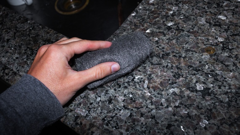 man cleaning counter with steel wool 
