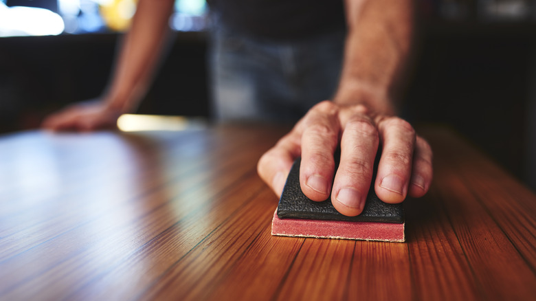 Hand holding sander on table