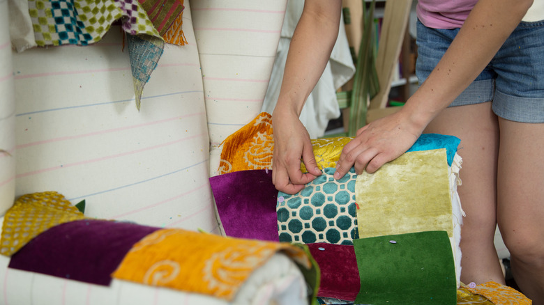 Women stitching cloth to chair