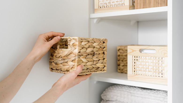 Hands placing basket on shelf