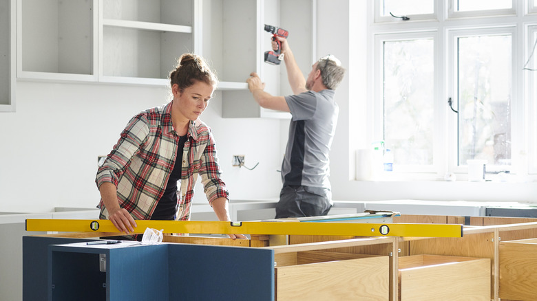 young woman and man building new kitchen cabinets