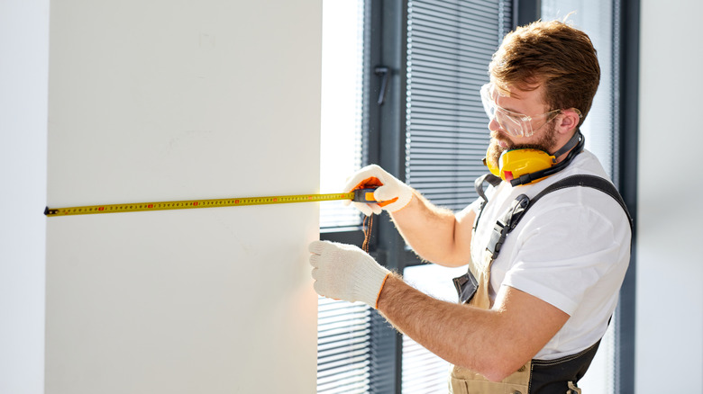 Person measuring length of wall