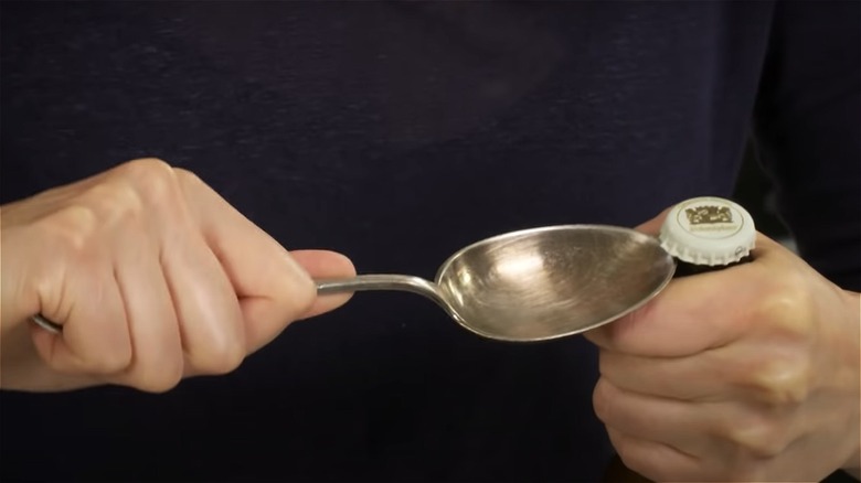 spoon prying off bottle cap