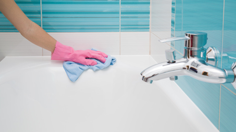 gloved hand wiping bathtub