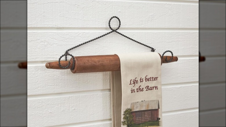 Rolling pin towel holder against a white wall