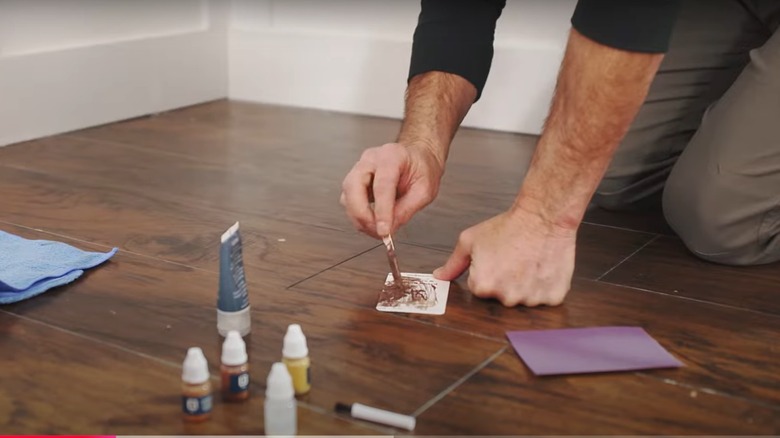 A person filling in a crack on a laminate floor