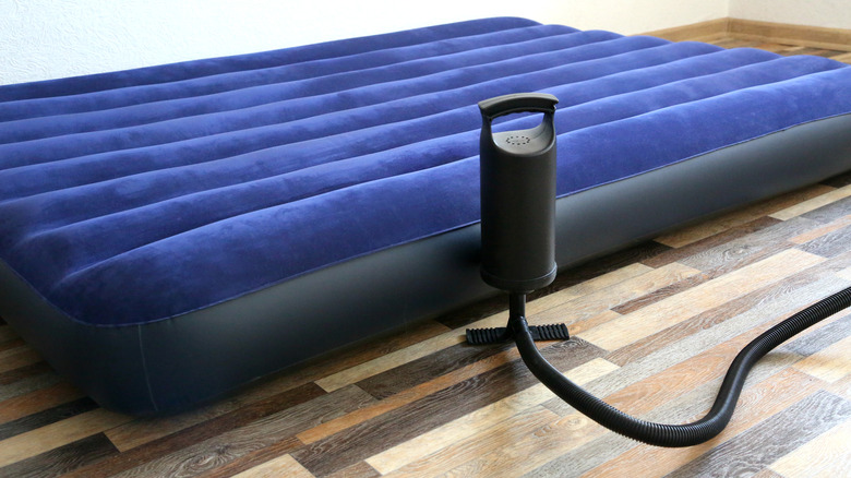 A blue mattress being inflated with a pump