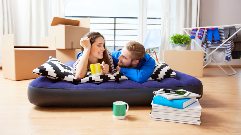 A couple lying on an air mattress in a new apartment