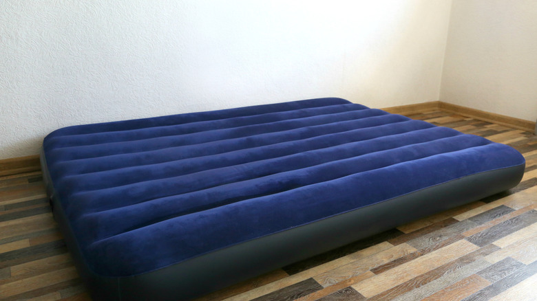 An inflated air mattress on the floor against a white wall