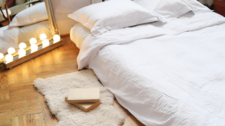 Air mattress with proper bedding and mirror, rug, and books around it