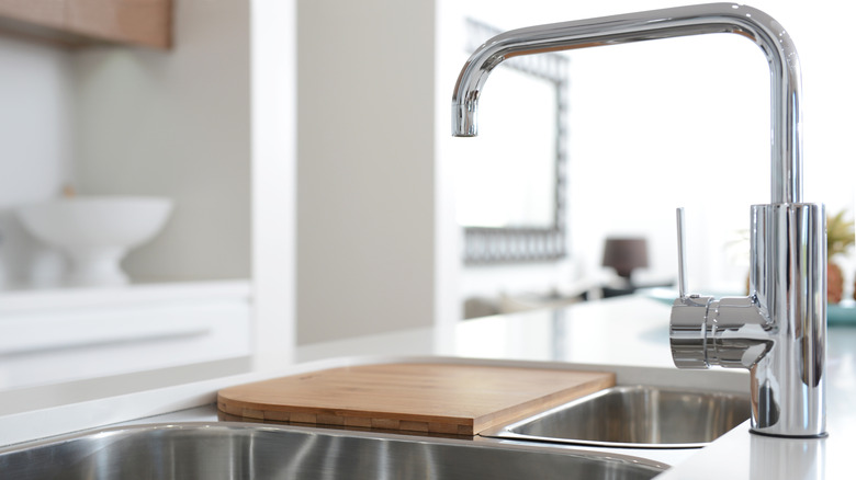 Wooden cutting board over sink in kitchen