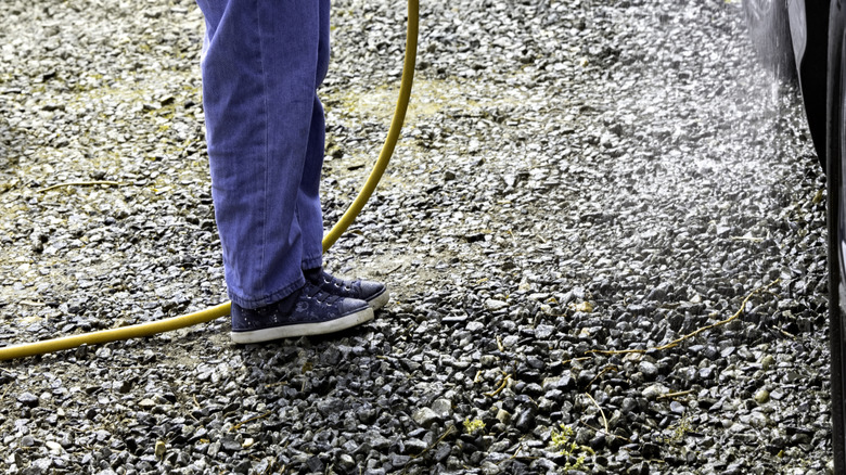 Girl holding a hose on a gravel driveway