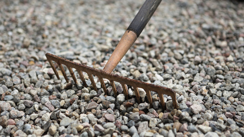 Person leveling a gravel surface with a rake