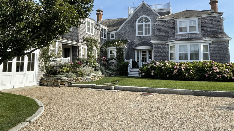 Gravel driveway in front of a large gray home