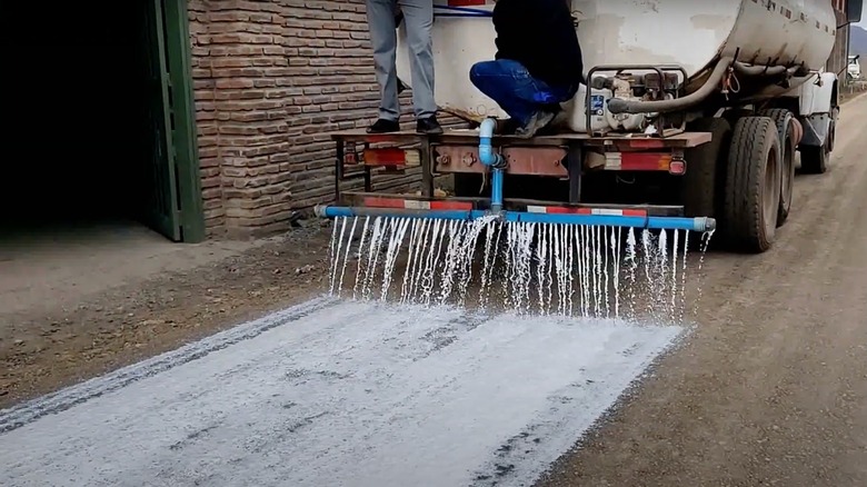 Truck spraying soil stabilizer on a gravel road