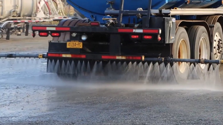 Truck spraying liquid calcium chloride on a dusty road