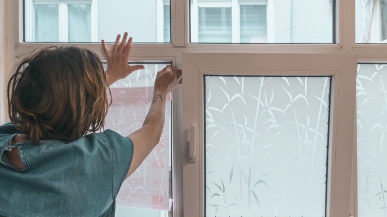 A person applying a peel and stick decorative window film to windows.