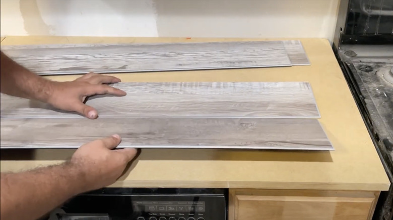 man laying thin wood planks over counter