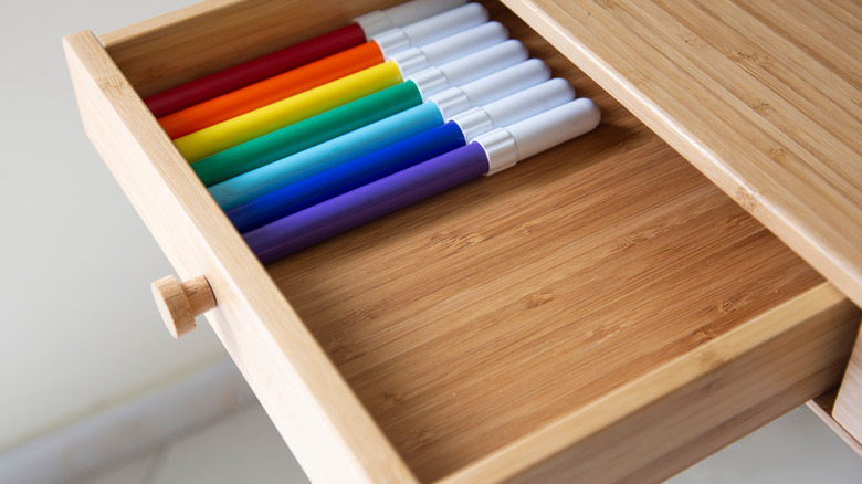 Colorful markers in wooden drawer