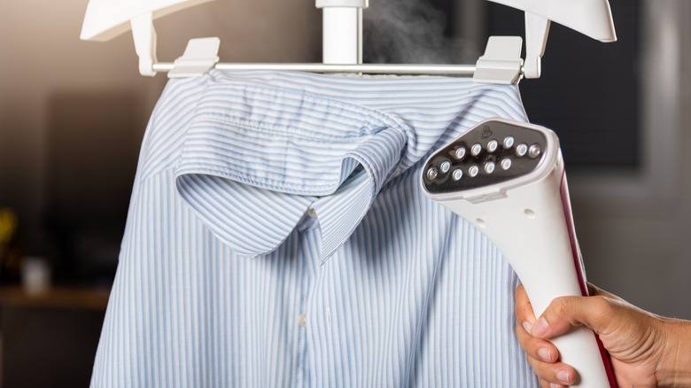 Person using clothes steamer without attachments