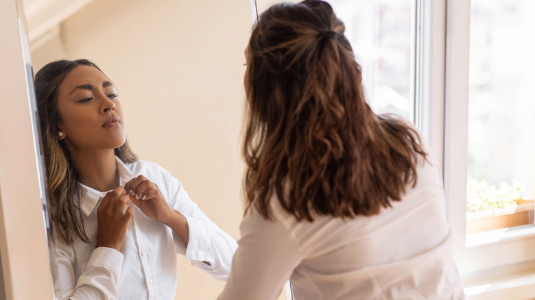 woman putting on freshly steamed shirt