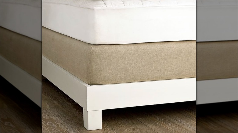 Bed with a tan linen box frame cover