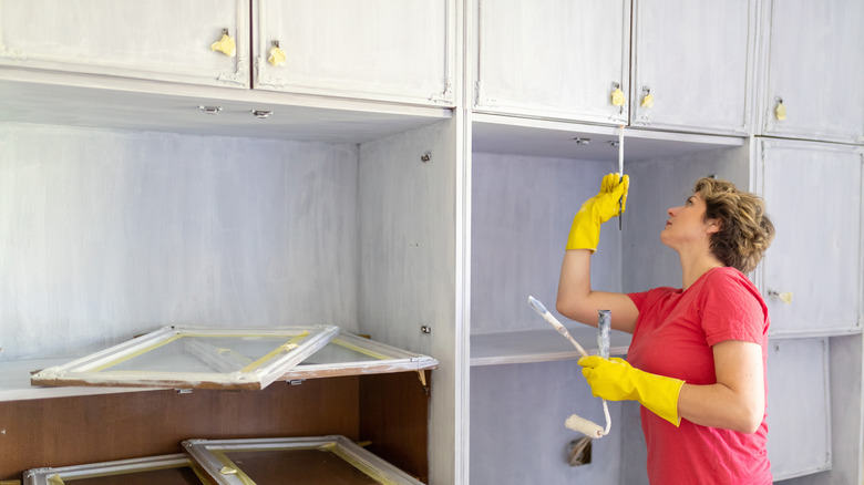 A person repainting kitchen cabinets