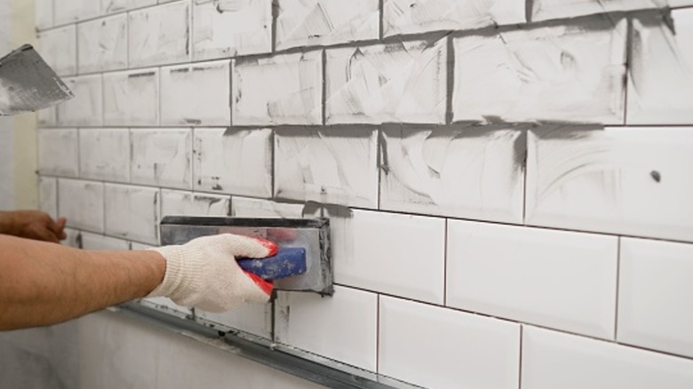 A person applying new grout to a backsplash