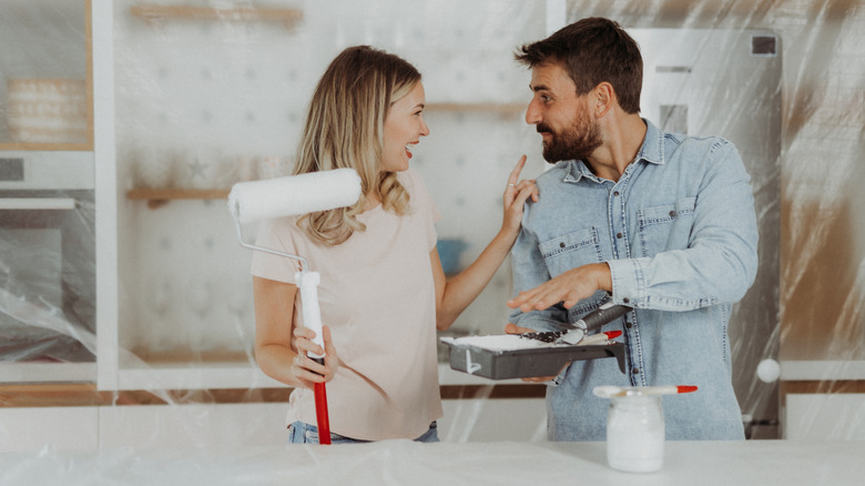 A couple with paint brushes in the kitchen