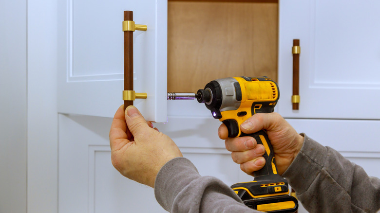 A person installing new cabinet handles