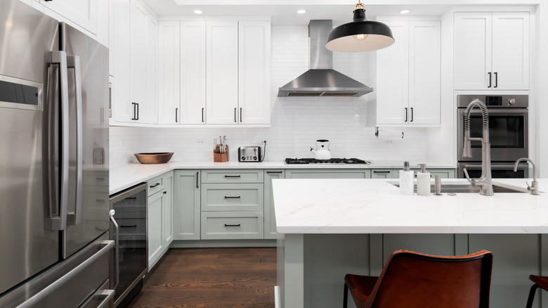 Dual-colored kitchen cabinets with white countertops and dark floors