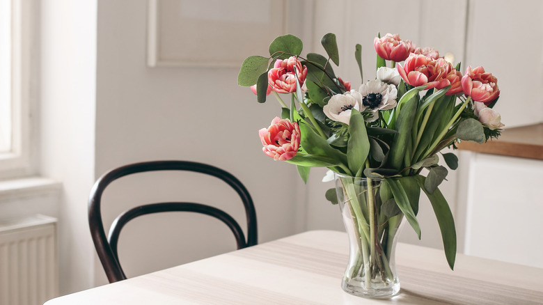 Spring flowers in glass vase on wooden table