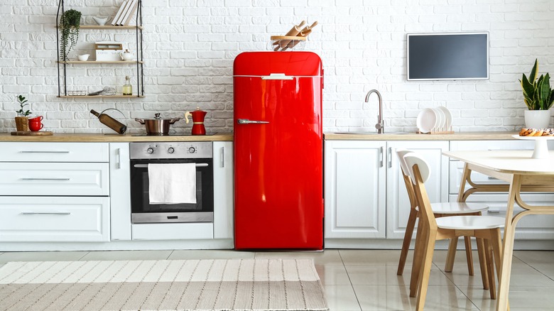 White kitchen with red fridge, white counters and dining table