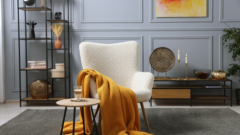 Living room interior with comfortable armchair, blanket and side table