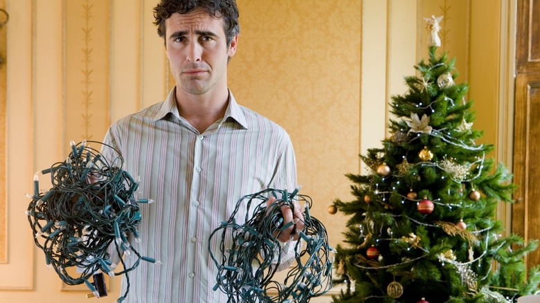 man holding tangled Christmas lights